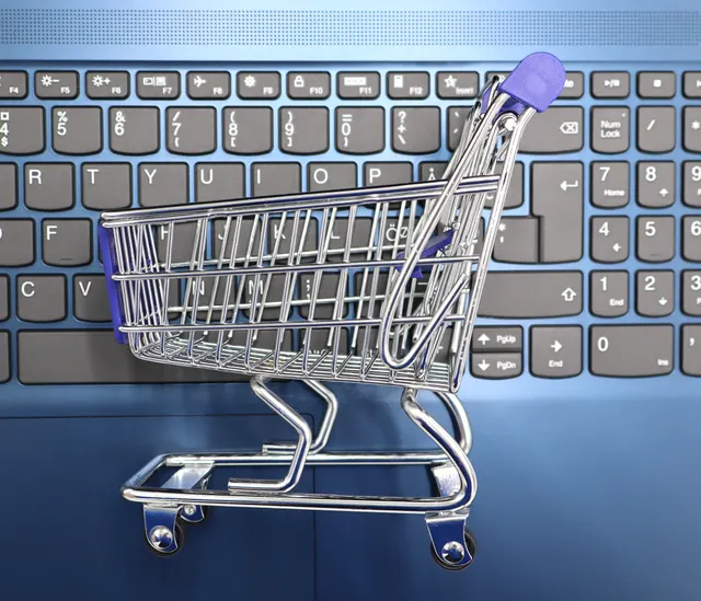 Miniature shopping cart on a laptop keyboard representing online retail