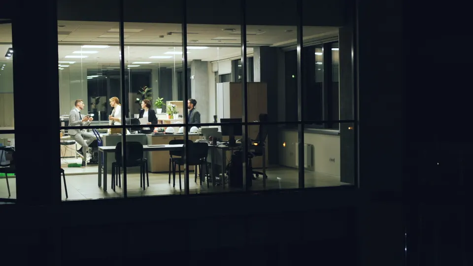 Professionals meeting late in a modern glass-walled office