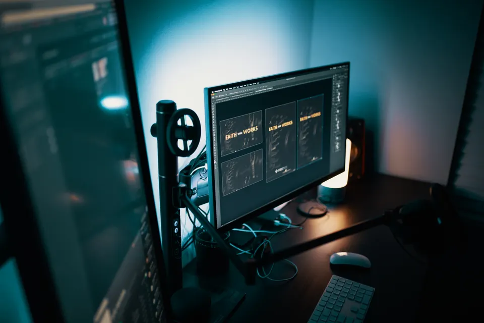 Dual monitors in a dimly lit studio displaying design and analytics software
